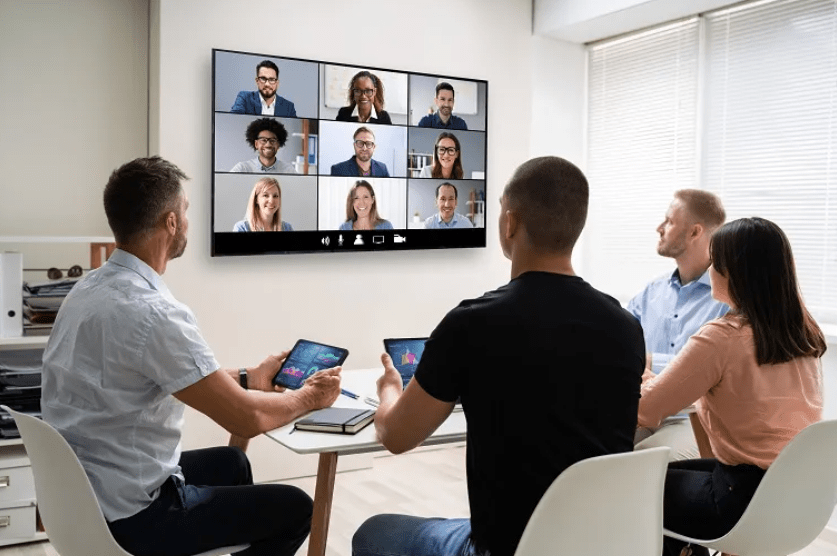 Team using AI-powered collaboration tools in a video conference meeting on large screen.